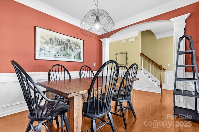 dining room featuring hardwood / wood-style flooring, ornate columns, and ornamental molding