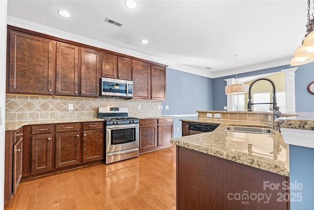 kitchen with sink, stainless steel appliances, decorative light fixtures, decorative backsplash, and ornamental molding