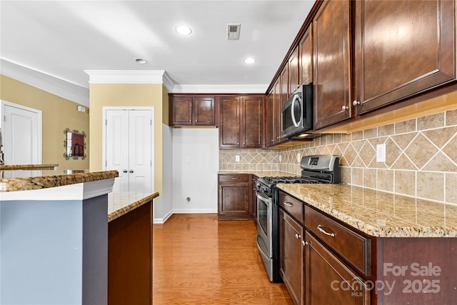 kitchen featuring light stone countertops, light hardwood / wood-style flooring, ornamental molding, and appliances with stainless steel finishes