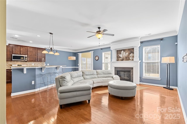 living room featuring crown molding, ceiling fan with notable chandelier, and hardwood / wood-style flooring