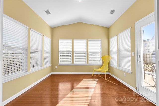 unfurnished room with hardwood / wood-style floors, plenty of natural light, and vaulted ceiling