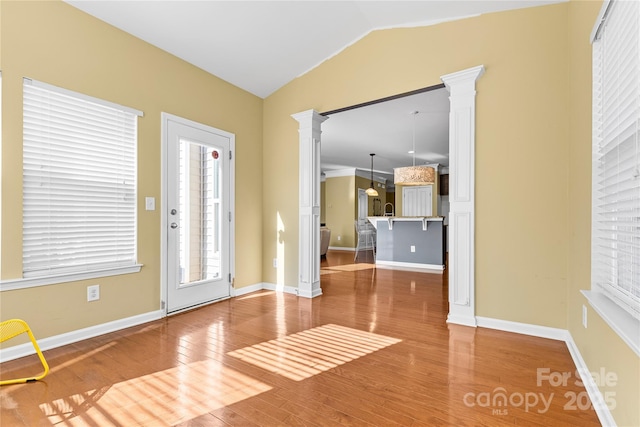 interior space featuring hardwood / wood-style floors, decorative columns, and lofted ceiling