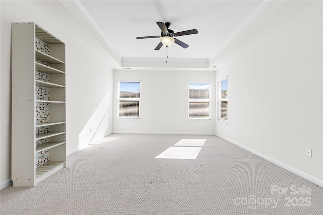 empty room featuring light carpet, a raised ceiling, ceiling fan, and crown molding