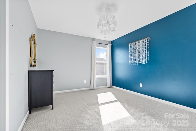 carpeted empty room with an inviting chandelier