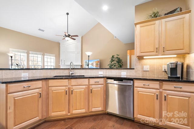 kitchen featuring kitchen peninsula, stainless steel dishwasher, dark wood-type flooring, sink, and dark stone countertops