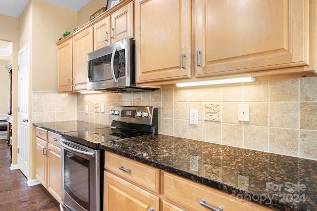 kitchen featuring tasteful backsplash, dark hardwood / wood-style flooring, dark stone countertops, light brown cabinetry, and appliances with stainless steel finishes