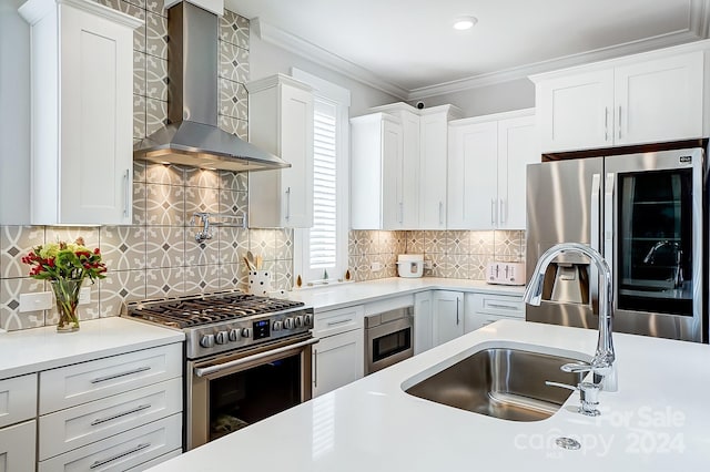 kitchen with white cabinets, backsplash, stainless steel appliances, and wall chimney range hood