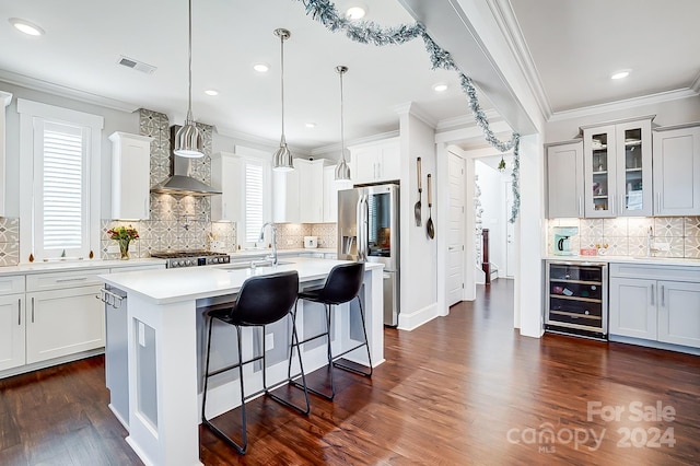 kitchen with appliances with stainless steel finishes, dark hardwood / wood-style flooring, decorative light fixtures, white cabinetry, and wine cooler