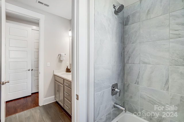 bathroom with vanity, tiled shower / bath, and hardwood / wood-style flooring