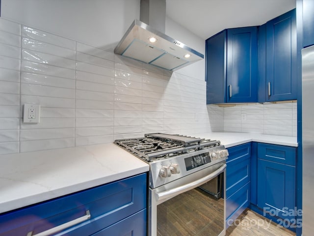 kitchen featuring high end stove, light stone counters, wall chimney exhaust hood, and backsplash