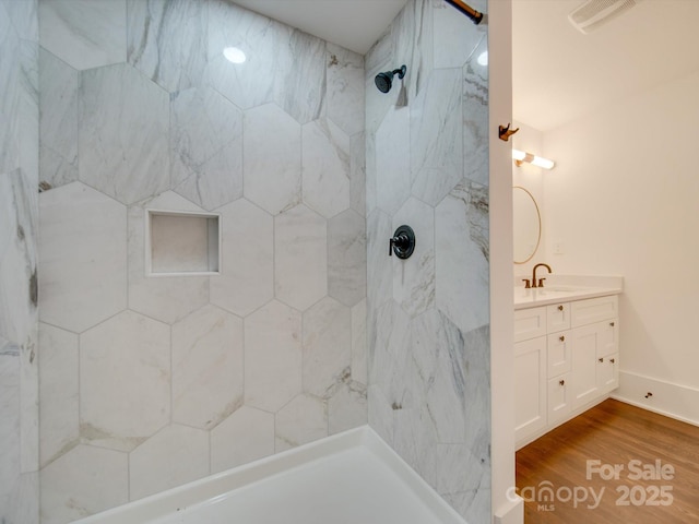 bathroom with a tile shower, vanity, and hardwood / wood-style flooring