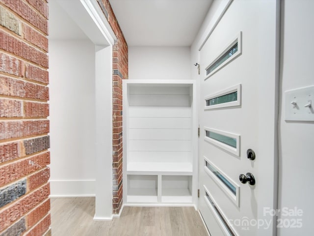 mudroom featuring light wood-type flooring and brick wall