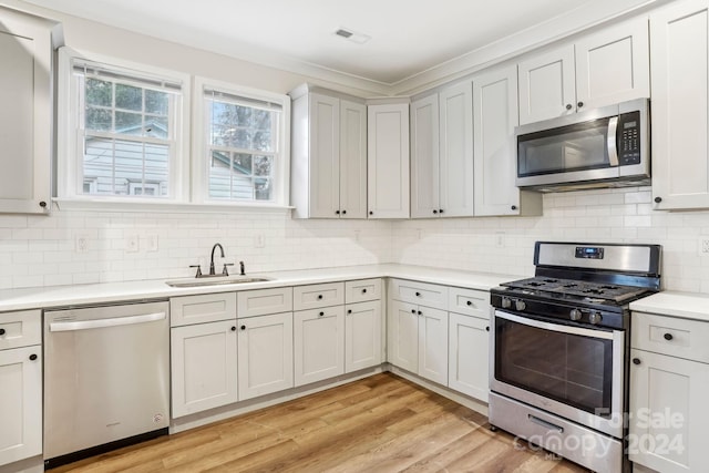 kitchen with decorative backsplash, sink, light wood-type flooring, and stainless steel appliances