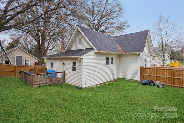 rear view of house featuring a wooden deck and a lawn