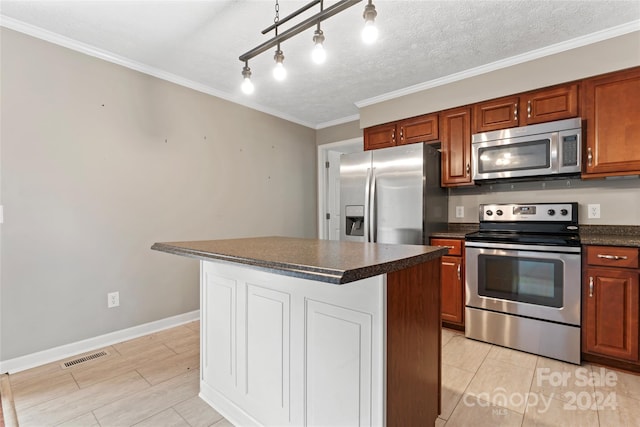 kitchen with a center island, rail lighting, crown molding, a textured ceiling, and appliances with stainless steel finishes