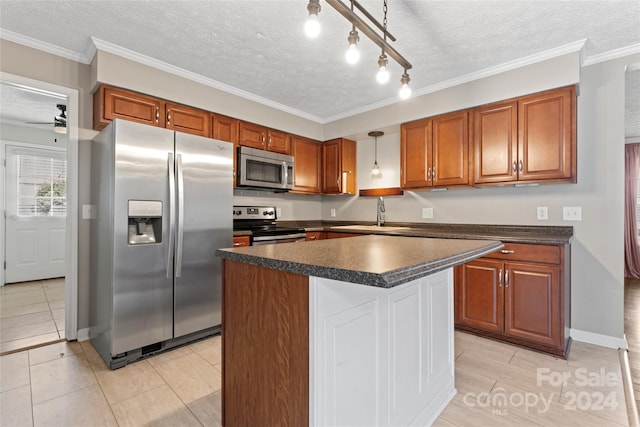 kitchen with hanging light fixtures, crown molding, a textured ceiling, appliances with stainless steel finishes, and a kitchen island