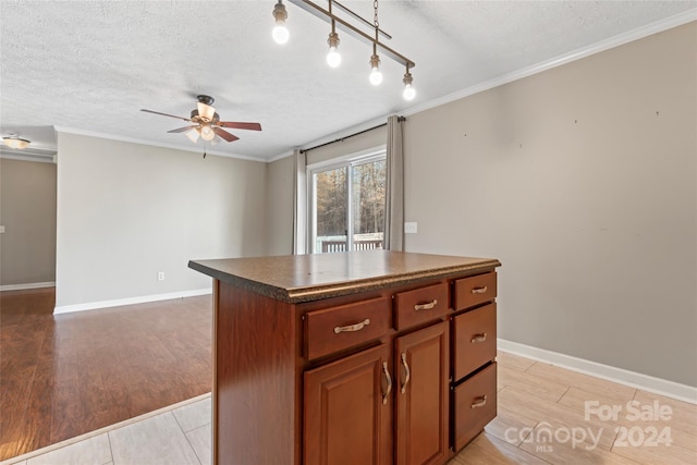 kitchen featuring ceiling fan, a kitchen island, a textured ceiling, and light hardwood / wood-style flooring