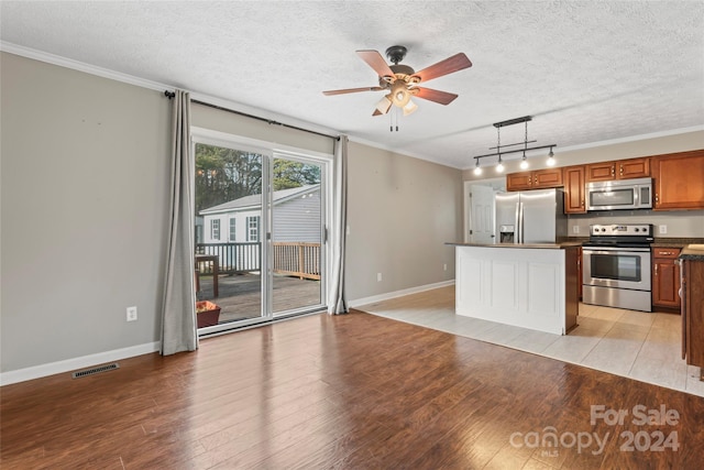 kitchen with a center island, decorative light fixtures, a textured ceiling, appliances with stainless steel finishes, and light wood-type flooring