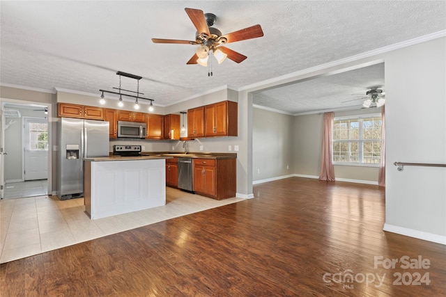 kitchen featuring a healthy amount of sunlight, light hardwood / wood-style floors, a textured ceiling, and appliances with stainless steel finishes