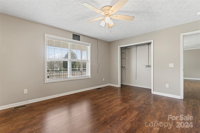 unfurnished bedroom featuring ceiling fan, dark hardwood / wood-style flooring, a textured ceiling, and a closet