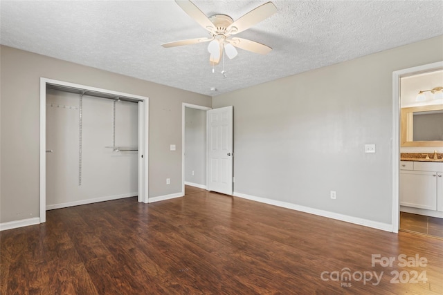 unfurnished bedroom with dark hardwood / wood-style flooring, a textured ceiling, ceiling fan, connected bathroom, and a closet