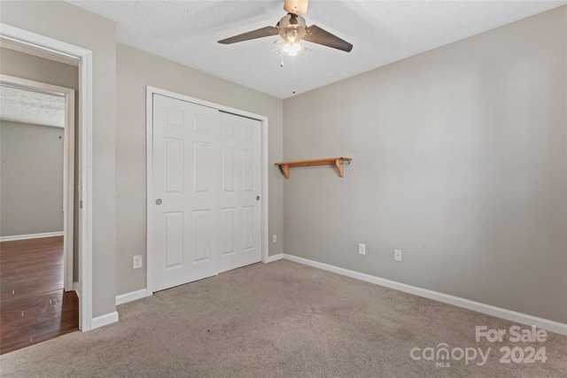 unfurnished bedroom with ceiling fan, carpet floors, a textured ceiling, and a closet