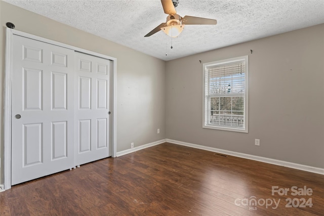 unfurnished bedroom featuring ceiling fan, dark hardwood / wood-style floors, a textured ceiling, and a closet