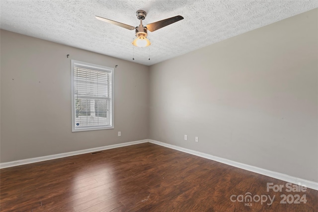 spare room with dark hardwood / wood-style floors, ceiling fan, and a textured ceiling