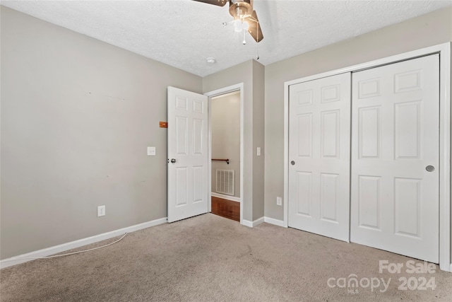 unfurnished bedroom with light carpet, a textured ceiling, a closet, and ceiling fan