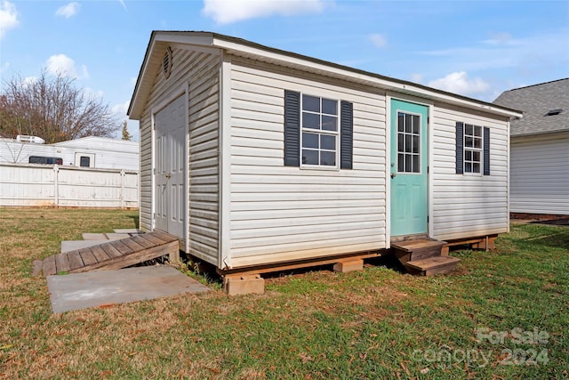 rear view of house featuring a lawn and an outdoor structure