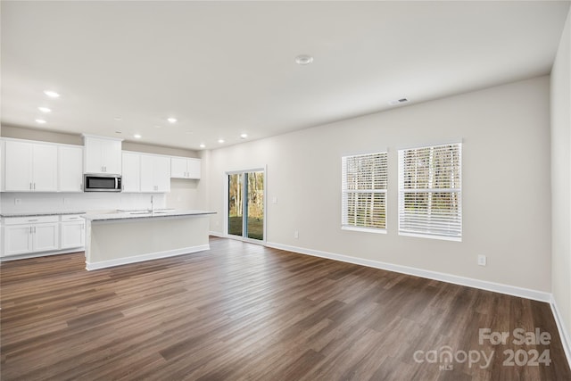 kitchen featuring white cabinetry, a center island with sink, and dark wood-type flooring