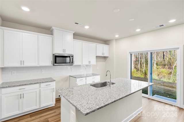 kitchen with white cabinets, sink, and a kitchen island with sink