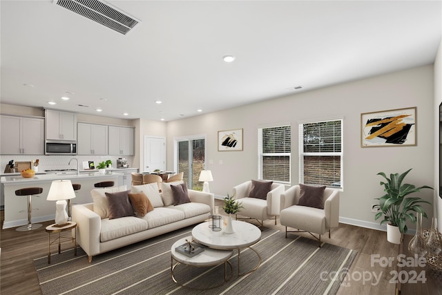 living room with a wealth of natural light and dark wood-type flooring