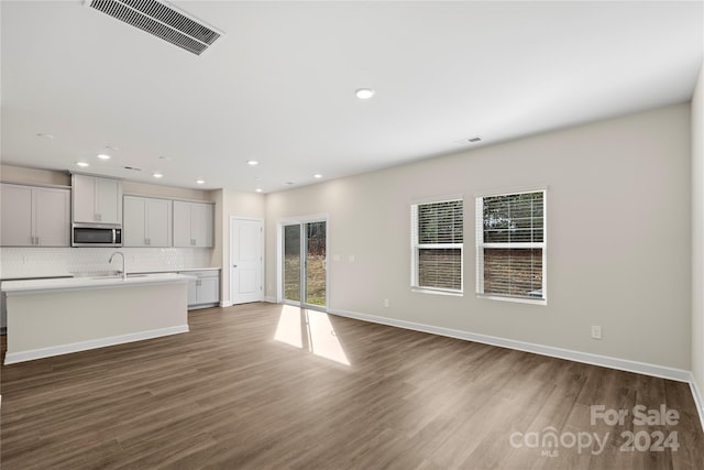 unfurnished living room featuring sink and dark wood-type flooring