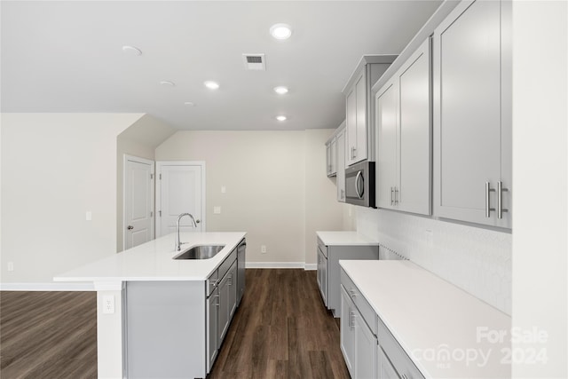 kitchen with gray cabinetry, sink, dark hardwood / wood-style flooring, a kitchen island with sink, and appliances with stainless steel finishes