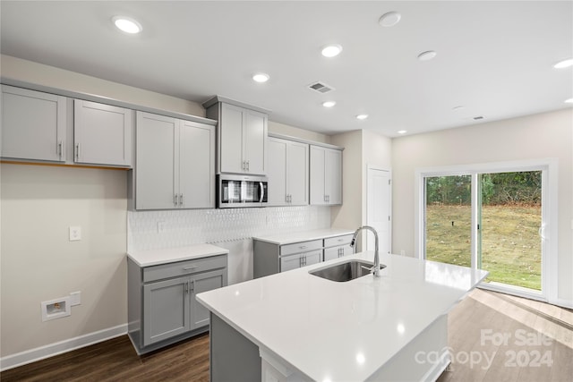 kitchen with dark hardwood / wood-style floors, a center island with sink, gray cabinetry, and sink