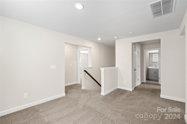 spare room featuring sink and light colored carpet