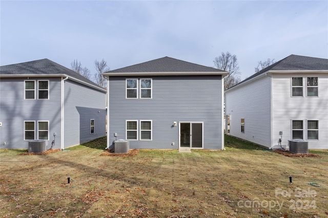 rear view of house with central AC unit and a yard