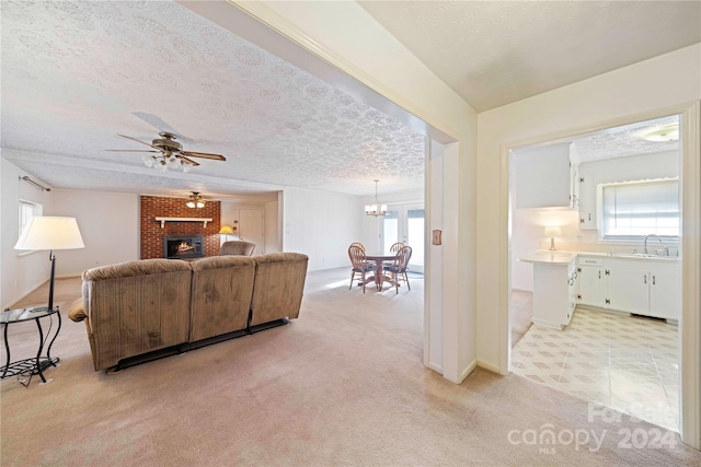 carpeted living room with ceiling fan, a textured ceiling, and a brick fireplace