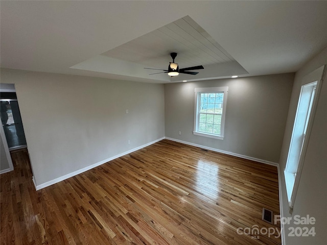 unfurnished room with hardwood / wood-style floors, a raised ceiling, and ceiling fan