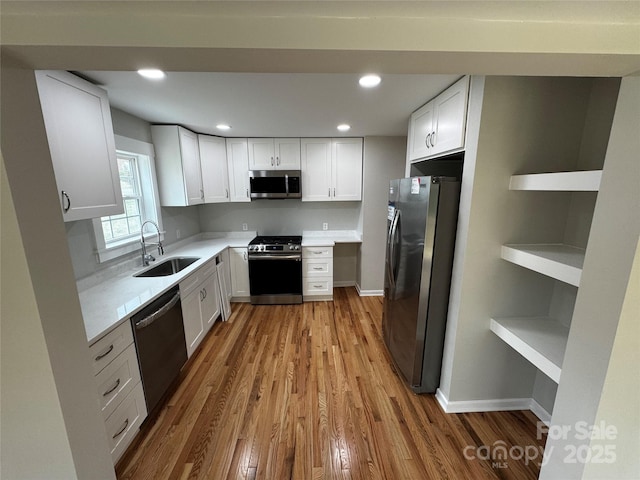 kitchen with white cabinetry, sink, light hardwood / wood-style flooring, and appliances with stainless steel finishes