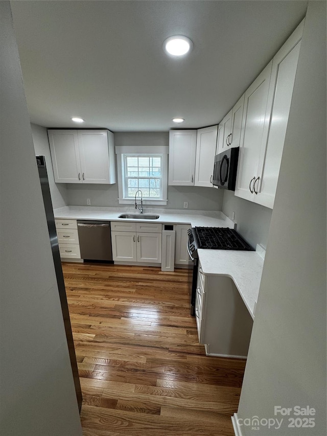 kitchen featuring sink, white cabinetry, wood-type flooring, gas stove, and stainless steel dishwasher