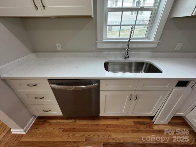 kitchen with white cabinetry, sink, light hardwood / wood-style flooring, and stainless steel dishwasher