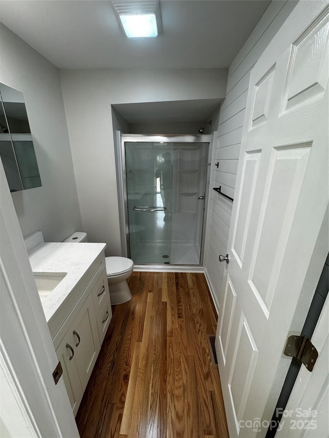 bathroom with vanity, hardwood / wood-style floors, a shower with shower door, and toilet