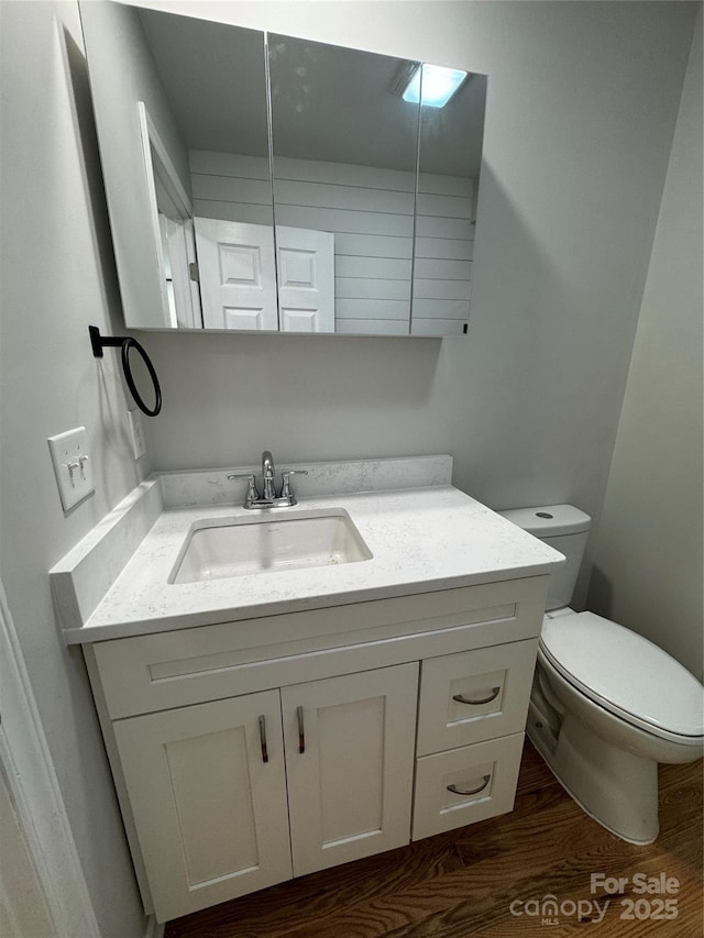 bathroom featuring vanity, wood-type flooring, and toilet