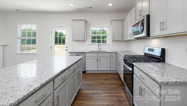 kitchen featuring decorative backsplash, appliances with stainless steel finishes, light stone counters, sink, and dark hardwood / wood-style floors