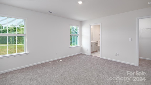 unfurnished bedroom with a walk in closet, a closet, and multiple windows