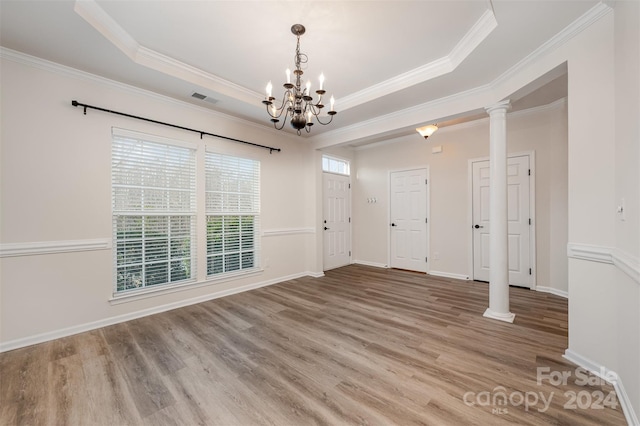 interior space featuring hardwood / wood-style floors, a raised ceiling, ornamental molding, and ornate columns