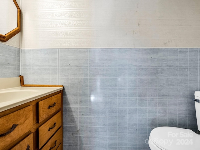 bathroom with vanity, toilet, and tile walls