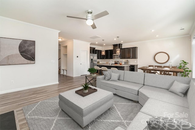 living room with ceiling fan, ornamental molding, dark hardwood / wood-style flooring, and sink